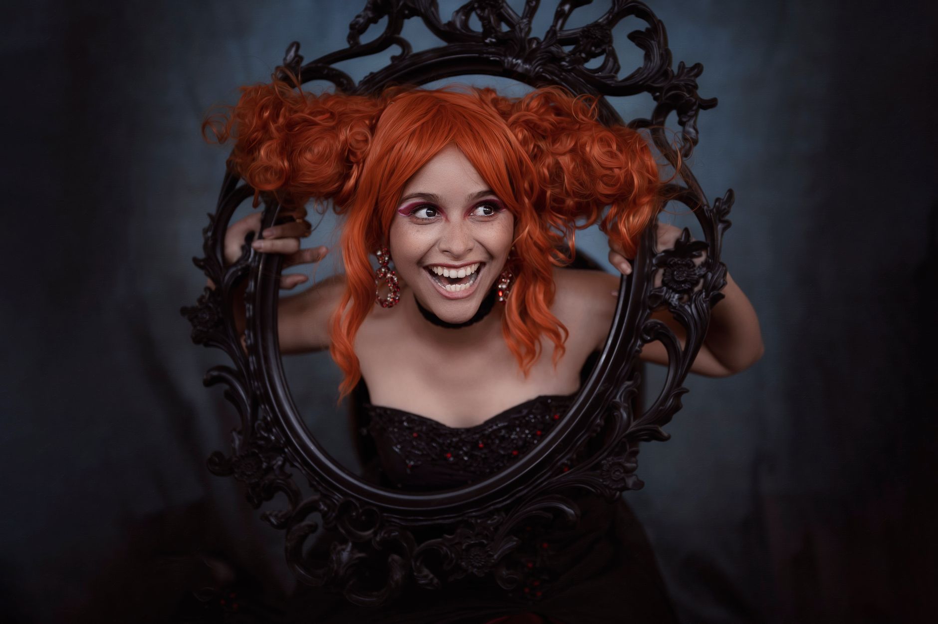 A lively portrait of a woman with orange hair posing through a decorative black frame, captured indoors. — Hedox Clinic Made