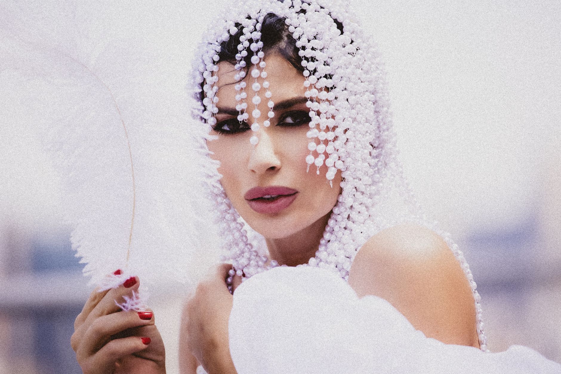 Elegant woman adorned in pearls holds a white feather, embodying grace and sophistication. — Jelly May Boost the Appearance o